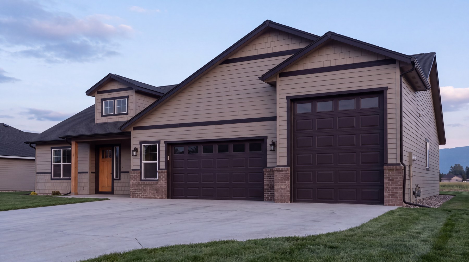 The Pendleton — three-car garage from the driveway at dusk